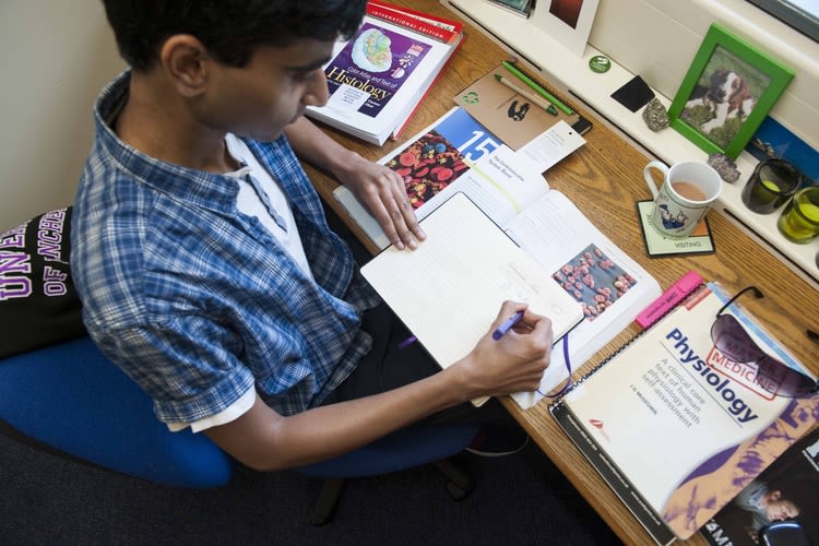 A student studying in the bedroom of a halls of residence.