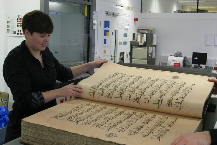 A member of library staff in Collections Care with an item from a collection
