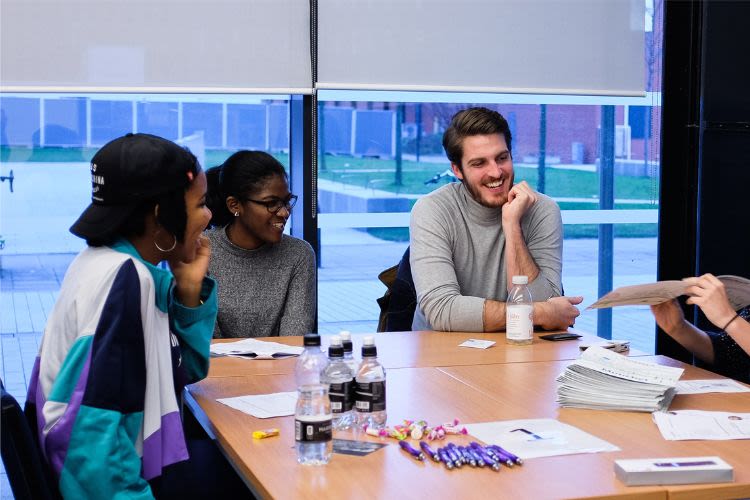 Students and a staff member doing group work while sitting around a table