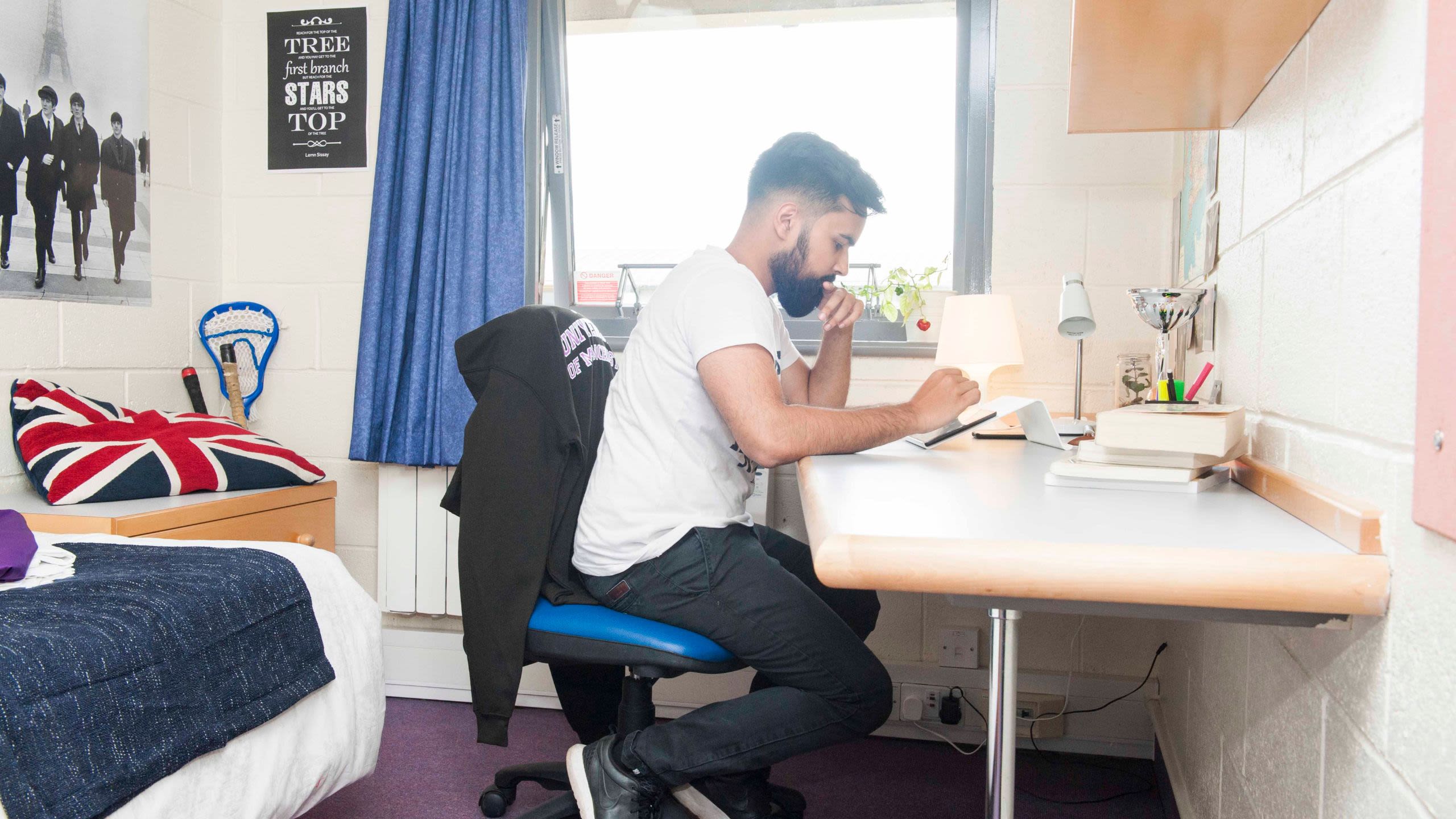 Student sat working at his desk in bedroom