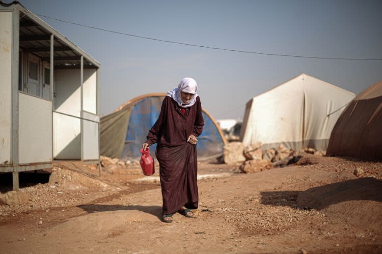 Woman walking with container for water in wartorn region