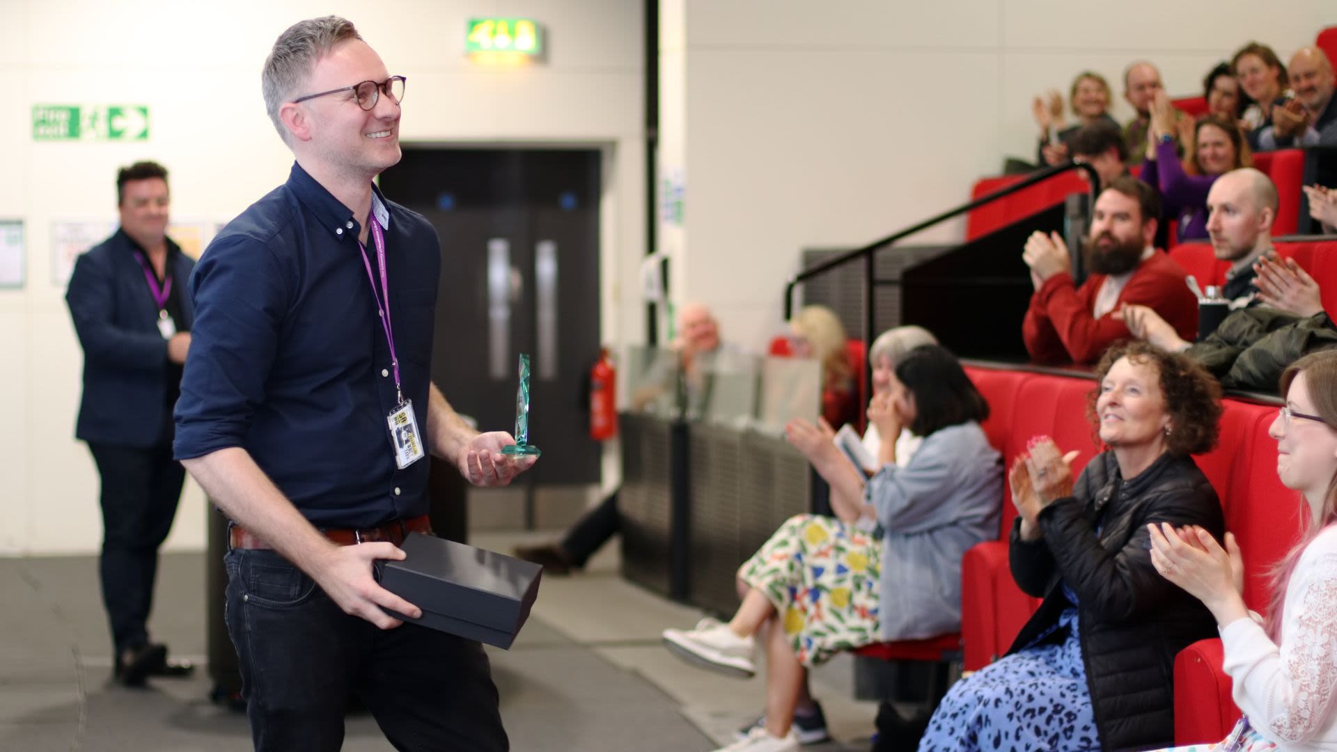 Mark smiling with his Staff Member of the Year award at the Rylands