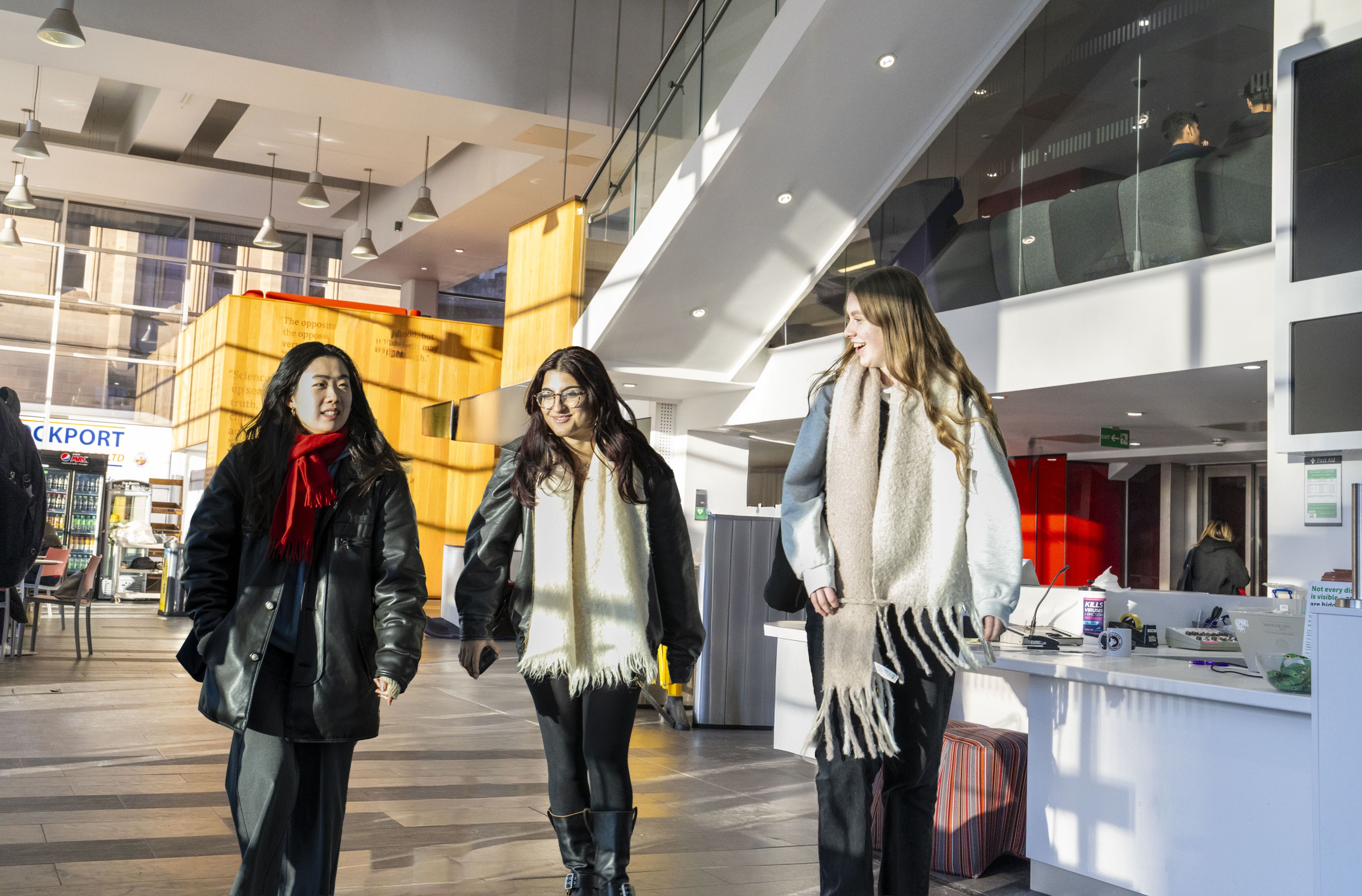 Three students walking through AGLC reception smiling