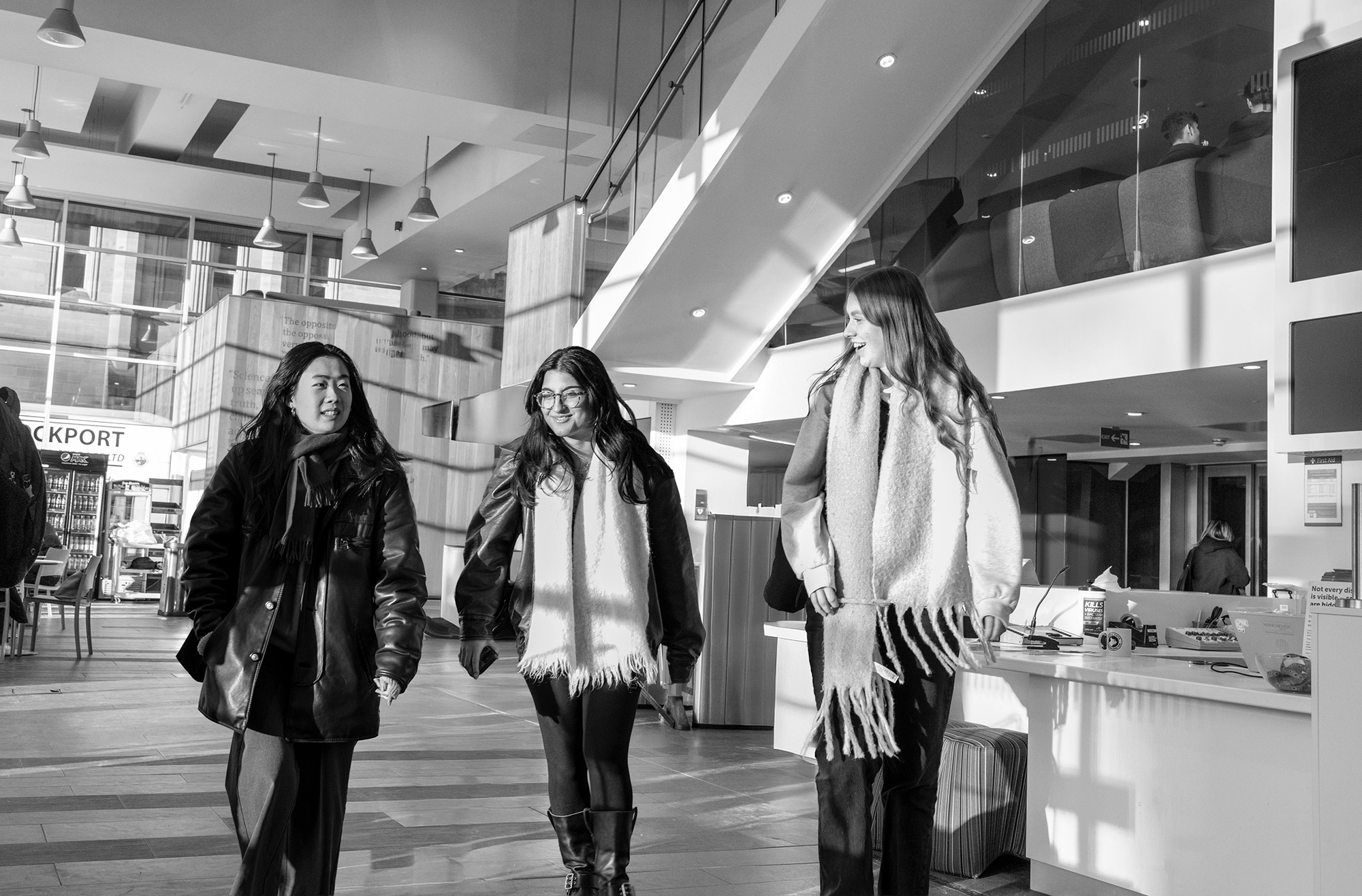 Three students walking through AGLC reception smiling