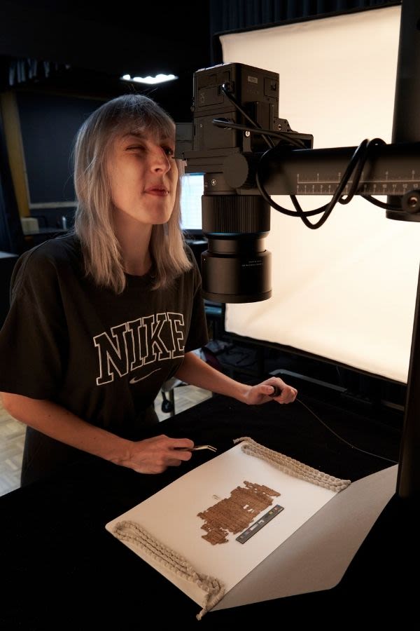 Photographer from imaging team looking at an item of papyri through lens in the imaging lab
