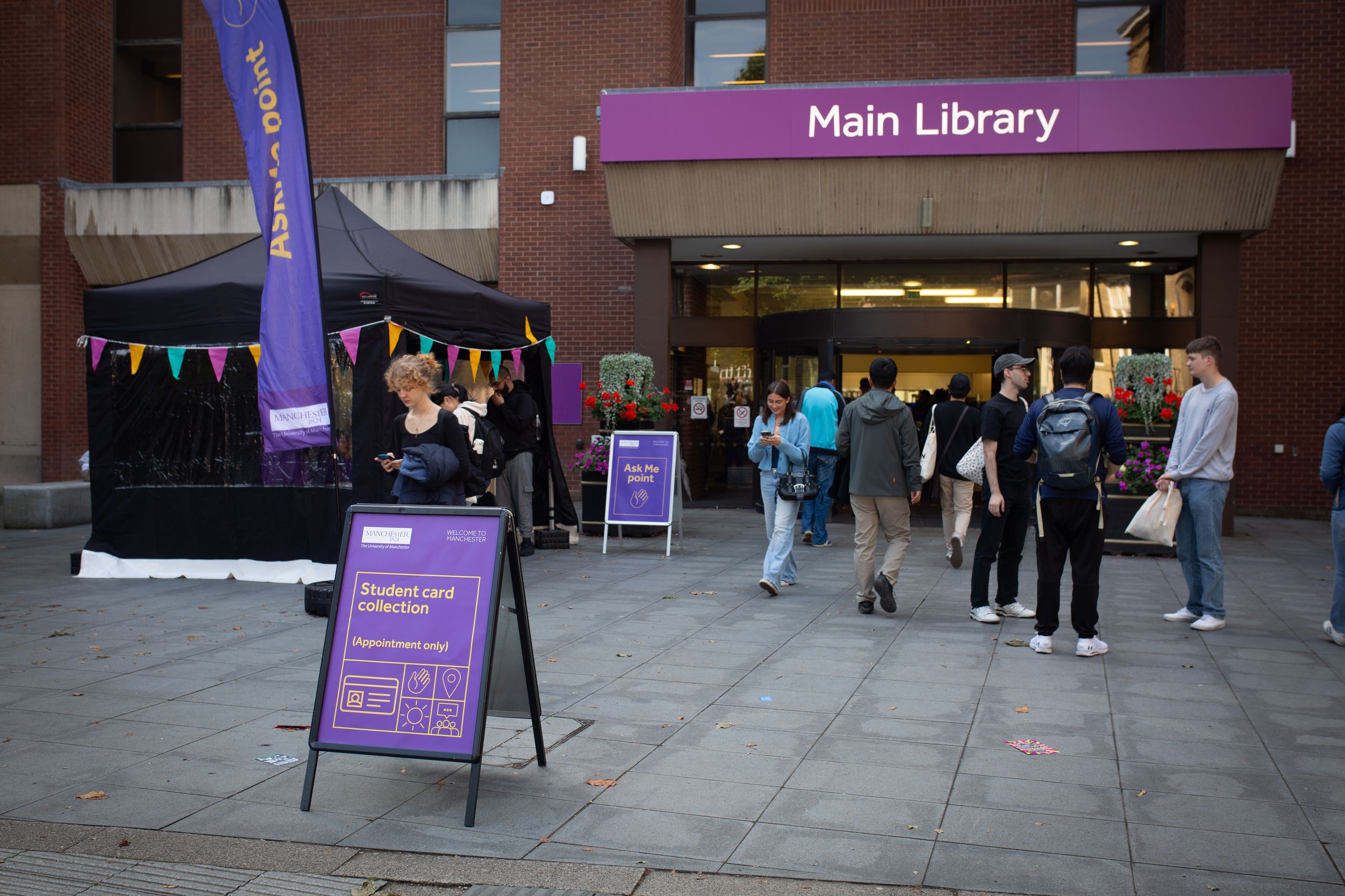 Student on laptop leaning against a wall in Blue 1