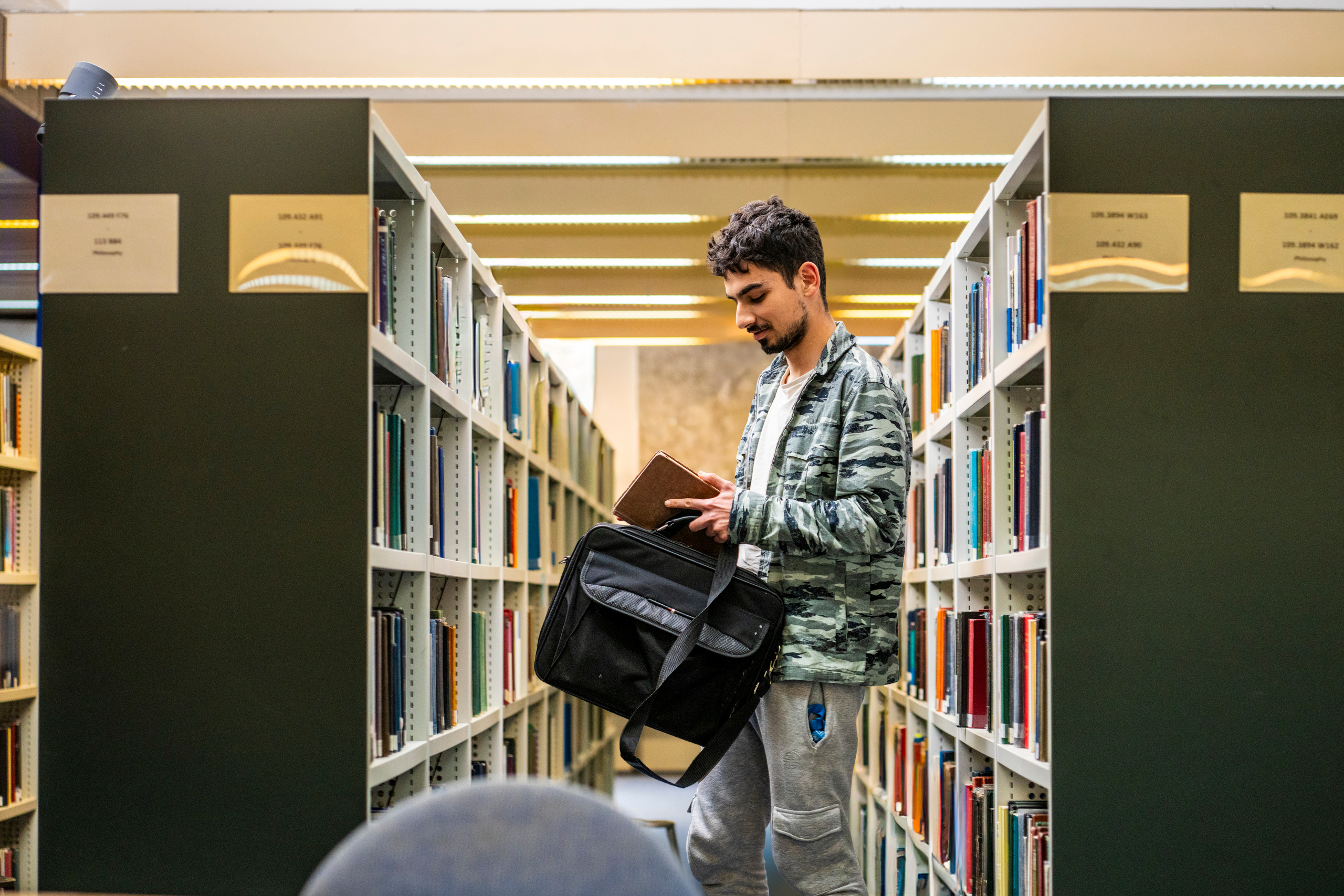 A student taking a book off a shelf in Main Library