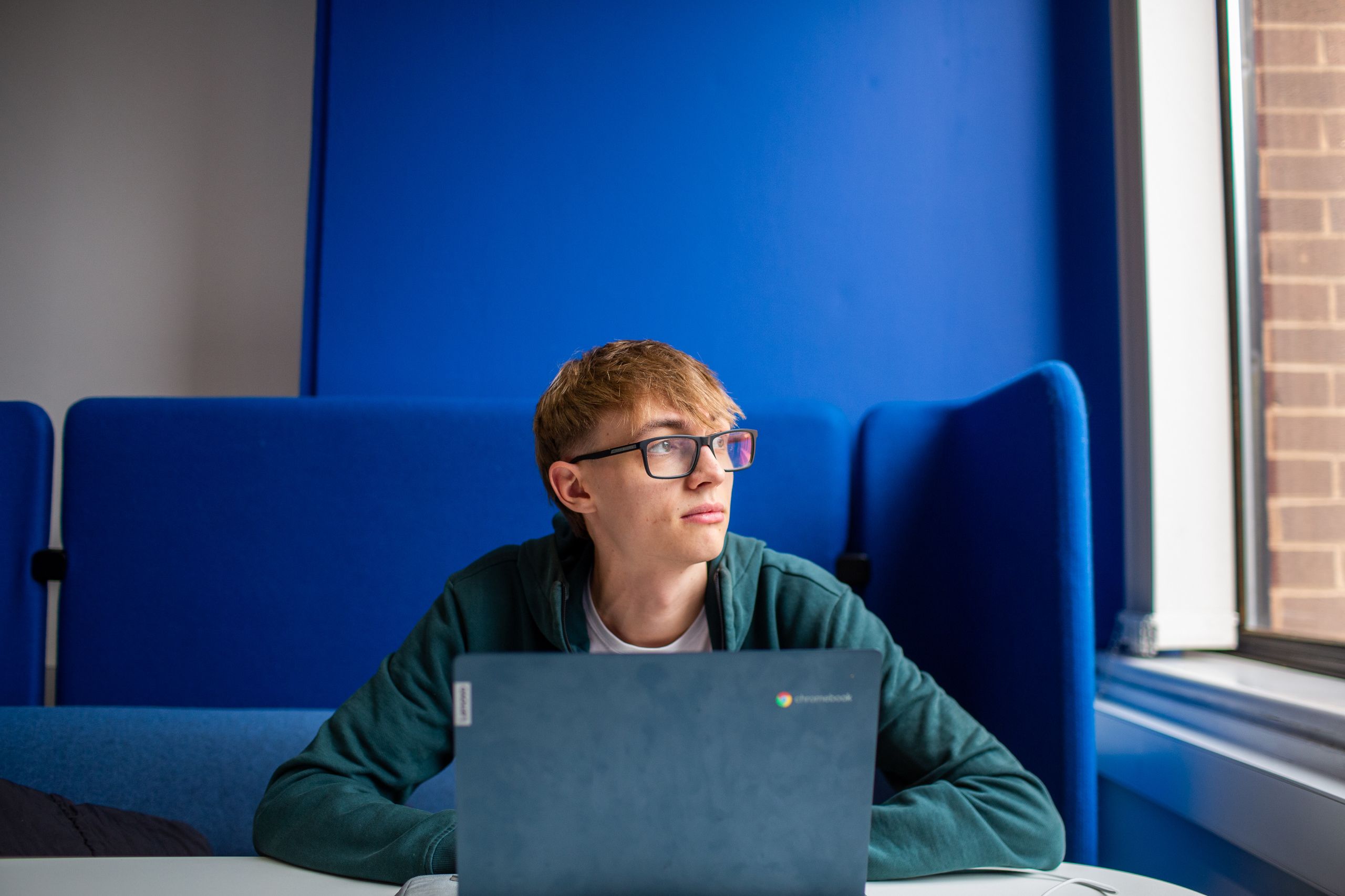 Student sitting at desk in Blue 1 in front of blue background